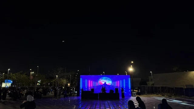 مسرح مضاء بأضواء زرقاء ووردية ، فعالية تكوة في جدة في المملكة العربية السعودية  17 يناير 2026،  تجربة شتوية تجمع بين الترفيه، التسوق، والمطاعم، تشمل الفعالية عرض موسيقي حي وفرق استعراضية متجولة،  مخصصة لجميع أفراد العائلة