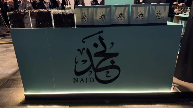 كشك يحمل كلمة نجد بخط عربي، فعالية تكوة في جدة في المملكة العربية السعودية  17 يناير 2026،  تجربة شتوية تجمع بين الترفيه، التسوق، والمطاعم، تشمل الفعالية عرض موسيقي حي وفرق استعراضية متجولة،  مخصصة لجميع أفراد العائلة