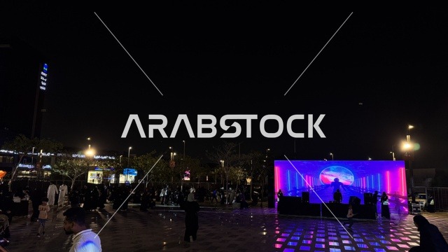 مسرح مضاء بأضواء زرقاء ووردية ، فعالية تكوة في جدة في المملكة العربية السعودية  17 يناير 2026،  تجربة شتوية تجمع بين الترفيه، التسوق، والمطاعم، تشمل الفعالية عرض موسيقي حي وفرق استعراضية متجولة،  مخصصة لجميع أفراد العائلة