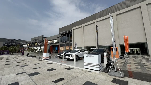 Parking in the outdoor parking lot of the U Walk complex in Jeddah, Saudi Arabia, an open walkway with a modern design, international and local restaurants and cafes, a comprehensive urban destination for walking, entertainment, and shopping, diverse brands, the exterior design of the Sinomi Mall building, seasonal events and recreational activities, outdoor seating and social spaces, vibrant family and youth atmosphere.
