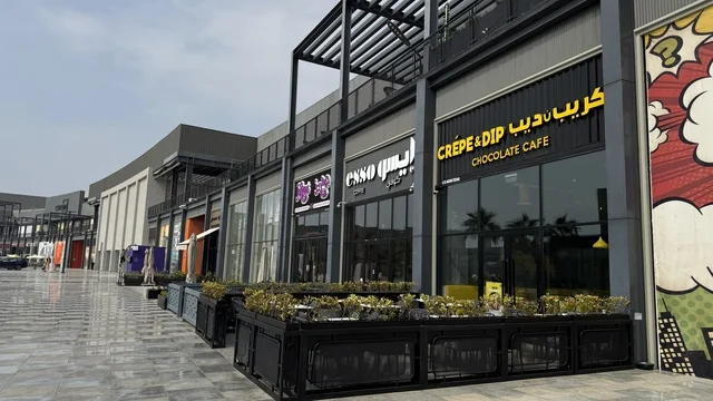 International and local restaurants and cafes at the U Walk complex in Jeddah, Saudi Arabia, February 15, 2024, an open walkway with a modern design, the exterior design of the Sinomi Mall building, a comprehensive urban destination for walking, entertainment, and shopping, outdoor seating and social spaces, a vibrant family and youth atmosphere.