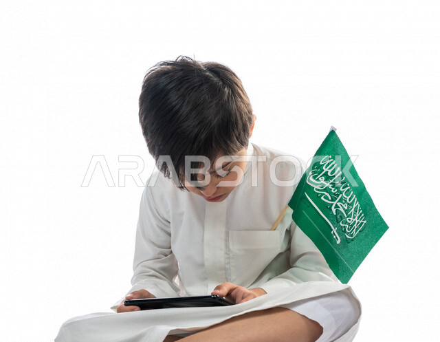 بورتريه لولد عربي خليجي سعودي مصاب بمتلازمة داون يقوم باستخدام الهاتف المحمول، قضاء وقت ممتع، انشطة فردية، أصحاب الهمم، ذوي الاحتياجات الخاصة، خلفية بيضاء