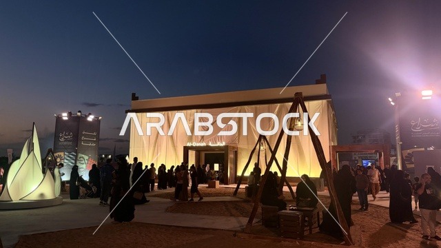 A temporary building resembling a tent, illuminated from the inside, the Wooden Ships Festival on the Al-Hamra Beach in Jeddah, Saudi Arabia, from January 12 to 16, 2026, showcases the stages of traditional shipbuilding, the tools and materials used, maritime heritage and coastal identity, interactive activities, and cultural performances.