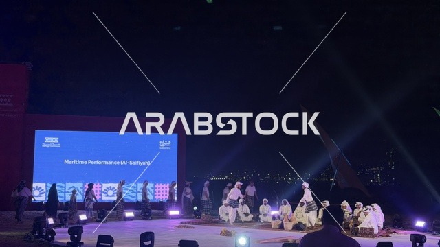 Live performance on an outdoor stage at night during the Wooden Ships Festival on Al-Hamra Beach in Jeddah, Saudi Arabia, from January 12 to 16, 2026, featuring displays of traditional shipbuilding stages, tools and materials used, maritime heritage and coastal identity, interactive activities, and cultural performances.