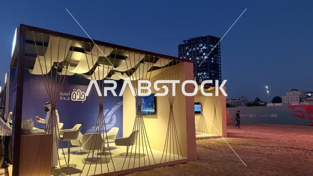 A temporary building resembling a tent, illuminated from the inside, the Wooden Ships Festival on the Al-Hamra Beach in Jeddah, Saudi Arabia, from January 12 to 16, 2026, showcases the stages of traditional shipbuilding, the tools and materials used, maritime heritage and coastal identity, interactive activities, and cultural performances.