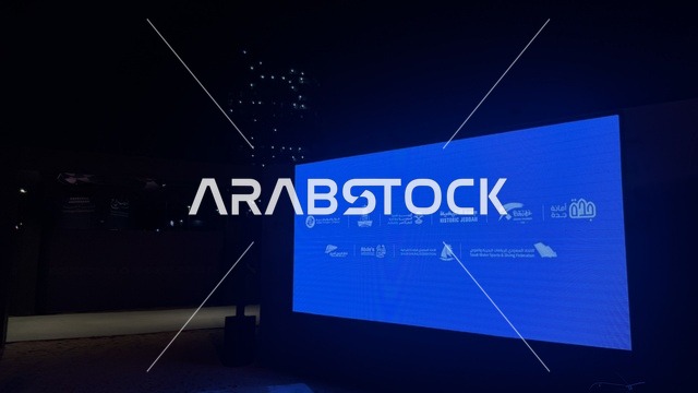 شاشة عرض كبيرة مضاءة باللون الأزرق، عروض لمراحل بناء السفن التقليدية والأدوات والمواد المستخدمة، مهرجان السفن الخشبية على شاطئ الحمراء بجدة في المملكة العربية السعودية 12 إلى 16 يناير 2026، التراث البحري، الأنشطة التفاعلية والعروض الثقافية