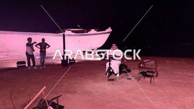 بجانب سفينة شخص يرتدي الزي التقليدي ويعزف على آلة موسيقية، عروض لمراحل بناء السفن التقليدية والأدوات والمواد المستخدمة، مهرجان السفن الخشبية على شاطئ الحمراء بجدة في المملكة العربية السعودية 12 إلى 16 يناير 2026، التراث البحري، الأنشطة التفاعلية والعروض الثقافية