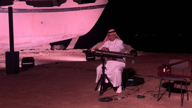شخص يرتدي الزي التقليدي ويعزف على آلة موسيقية، عروض لمراحل بناء السفن التقليدية والأدوات والمواد المستخدمة، مهرجان السفن الخشبية على شاطئ الحمراء بجدة في المملكة العربية السعودية 12 إلى 16 يناير 2026، التراث البحري، الأنشطة التفاعلية والعروض الثقافية