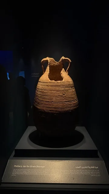 Below the ceramic jar is information about it, the Wooden Ships Festival on the Al-Hamra Beach in Jeddah, Saudi Arabia, from January 12 to 16, 2026, maritime heritage, interactive activities, and cultural performances, showcases of the stages of traditional shipbuilding and the tools and materials used.