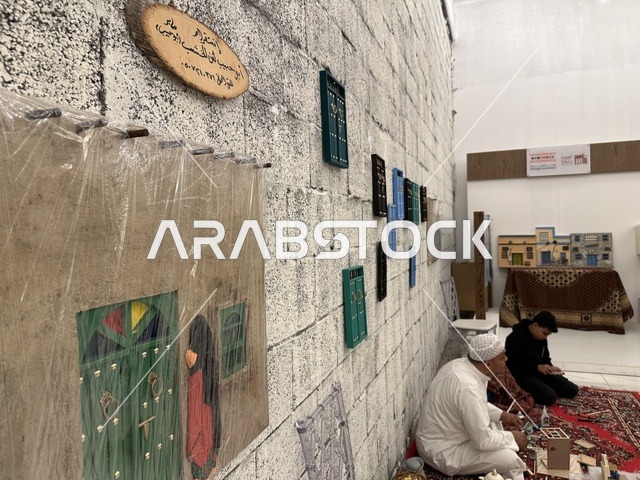 شخصان جالسان على سجادة حمراء يعملان على مجسمات، تجربة تسوق مابين عبق الزمان وأصالة المكان، فعالية حياة زمان في المنطقة الشرقية الدمام خلال شهر يناير 2026 في المملكة العربية السعودية، ملامح الماضي وحياة القديمة من خلال أجواء تراثية