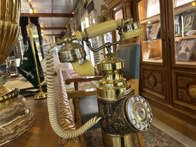 A decorative brass rotary phone at the Al-Falwah and Al-Jawhara Museum in the Al-Nuzha neighborhood of Dammam, Eastern Province, Saudi Arabia, on February 21, 2018, a distinctive educational and tourist destination, Saudi heritage, classic cars, a heritage and cultural landmark showcasing the history of traditional clothing and jewelry, documentation of handicrafts and Saudi identity, Islamic art.