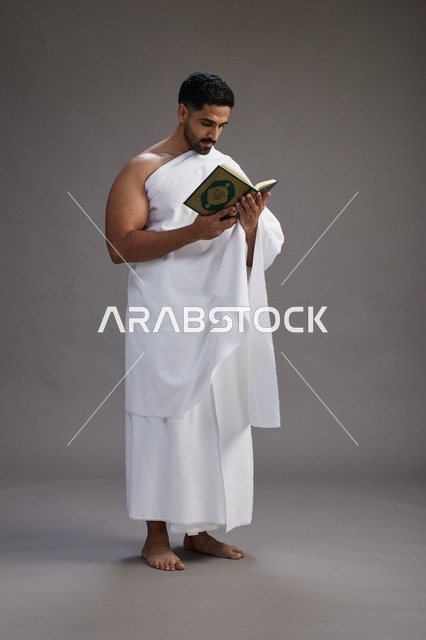 بورتريه لرجل سعودي بملابس الإحرام يقرأ القرآن أثناء الحج,  الجسم بالطول الكامل ,خلفيه رماديه