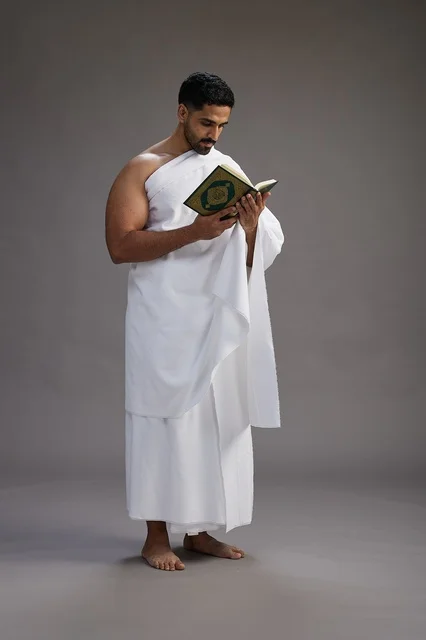 بورتريه لرجل سعودي بملابس الإحرام يقرأ القرآن أثناء الحج,  الجسم بالطول الكامل ,خلفيه رماديه