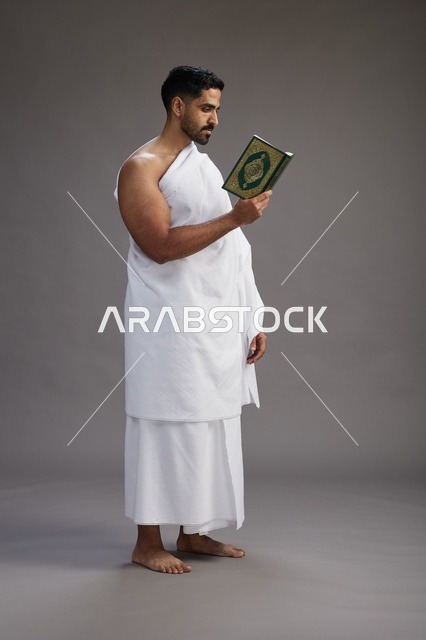 بورتريه لرجل سعودي بملابس الإحرام يقرأ القرآن أثناء الحج,  الجسم بالطول الكامل ,خلفيه رماديه