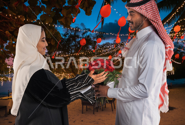 صورة زوجان سعيدان يحتفلان بعيد الحب , الزوج يقدم لزوجته باقة ورد , الزوجة تعبر بإيماءات وجه ويدين تدل على الدهشة والفرح , عيد الأم , يوم الفلنتاين , أعياد ومناسبات , عيد الميلاد , خلفية الحب والرومانسية .