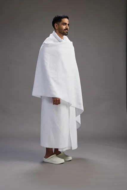 بورتريه لرجل عربي سعودي خليجي يرتدي ملابس الإحرام لأداء مناسك الحج, العباده والتقرب الى الله , الحج والعمره في مكه, الجسم بالطول الكامل , خلفيه رماديه