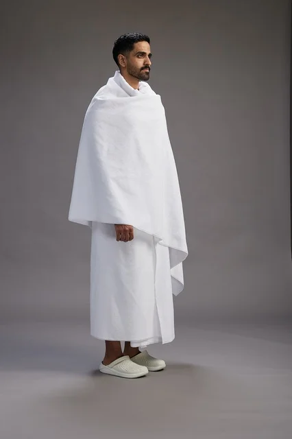 بورتريه لرجل عربي سعودي خليجي يرتدي ملابس الإحرام لأداء مناسك الحج, العباده والتقرب الى الله , الحج والعمره في مكه, الجسم بالطول الكامل , خلفيه رماديه