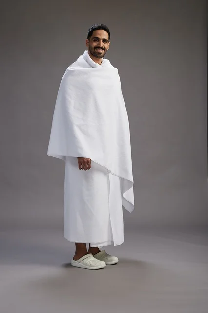 بورتريه لرجل عربي سعودي خليجي يرتدي ملابس الإحرام لأداء مناسك الحج, العباده والتقرب الى الله , الحج والعمره في مكه, الجسم بالطول الكامل , خلفيه رماديه