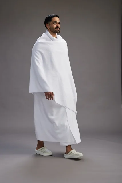 بورتريه لرجل عربي سعودي خليجي يرتدي ملابس الإحرام لأداء مناسك الحج, العباده والتقرب الى الله , الحج والعمره في مكه, الجسم بالطول الكامل , خلفيه رماديه