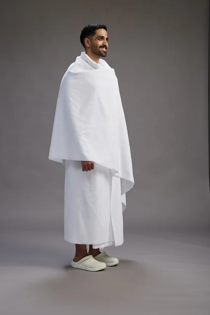 بورتريه لرجل عربي سعودي خليجي يرتدي ملابس الإحرام لأداء مناسك الحج, العباده والتقرب الى الله , الحج والعمره في مكه, الجسم بالطول الكامل , خلفيه رماديه