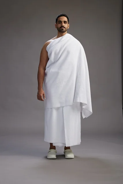 بورتريه لرجل عربي سعودي خليجي يرتدي ملابس الإحرام لأداء مناسك الحج, العباده والتقرب الى الله , الحج والعمره في مكه, الجسم بالطول الكامل , خلفيه رماديه
