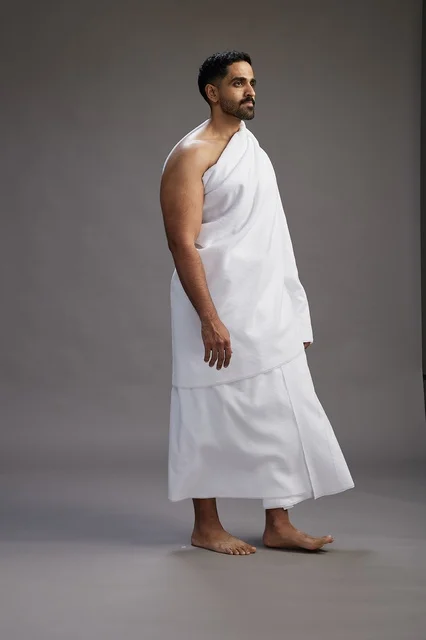 بورتريه لرجل عربي سعودي خليجي يرتدي ملابس الإحرام لأداء مناسك الحج, العباده والتقرب الى الله , الحج والعمره في مكه, الجسم بالطول الكامل , خلفيه رماديه
