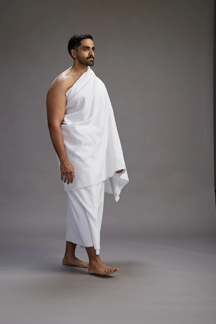 بورتريه لرجل عربي سعودي خليجي يرتدي ملابس الإحرام لأداء مناسك الحج, العباده والتقرب الى الله , الحج والعمره في مكه, الجسم بالطول الكامل , خلفيه رماديه