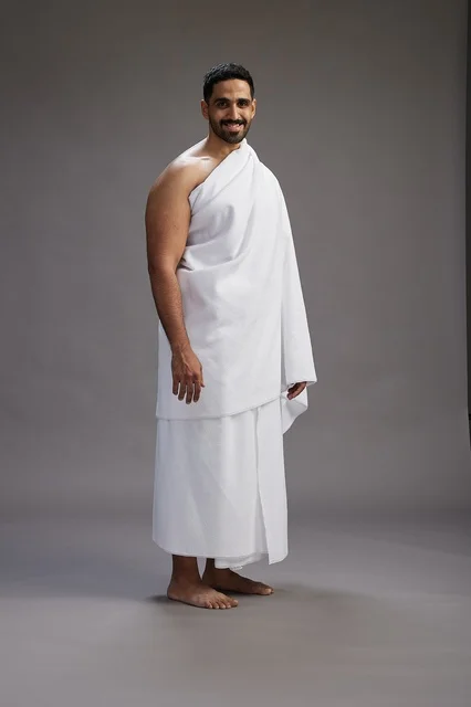 بورتريه لرجل عربي سعودي خليجي يرتدي ملابس الإحرام لأداء مناسك الحج, العباده والتقرب الى الله , الحج والعمره في مكه, الجسم بالطول الكامل , خلفيه رماديه