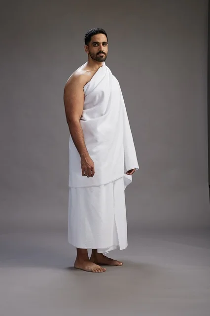 بورتريه لرجل عربي سعودي خليجي يرتدي ملابس الإحرام لأداء مناسك الحج, العباده والتقرب الى الله , الحج والعمره في مكه, الجسم بالطول الكامل , خلفيه رماديه