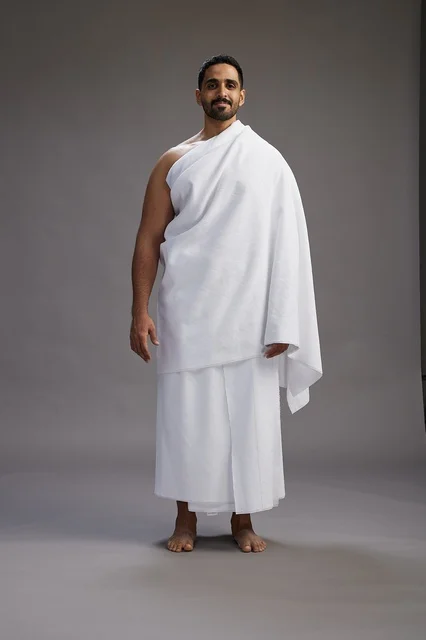بورتريه لرجل عربي سعودي خليجي يرتدي ملابس الإحرام لأداء مناسك الحج, العباده والتقرب الى الله , الحج والعمره في مكه, الجسم بالطول الكامل , خلفيه رماديه