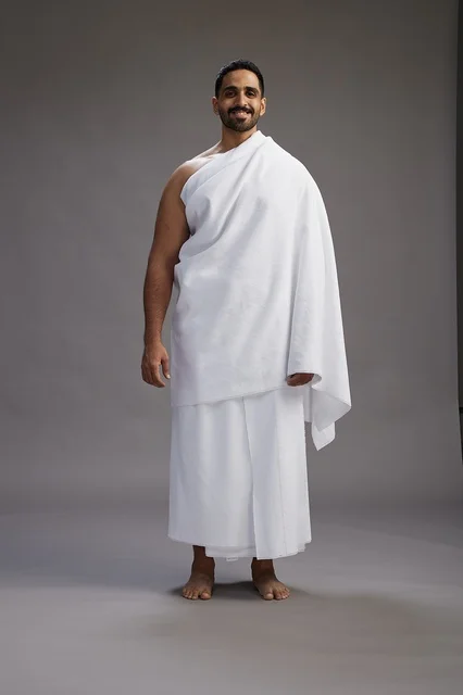 بورتريه لرجل عربي سعودي خليجي يرتدي ملابس الإحرام لأداء مناسك الحج, العباده والتقرب الى الله , الحج والعمره في مكه, الجسم بالطول الكامل , خلفيه رماديه
