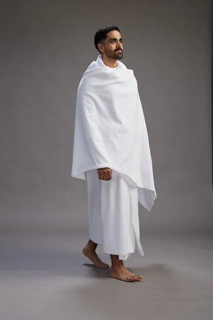 بورتريه لرجل عربي سعودي خليجي يرتدي ملابس الإحرام لأداء مناسك الحج, العباده والتقرب الى الله , الحج والعمره في مكه, الجسم بالطول الكامل , خلفيه رماديه