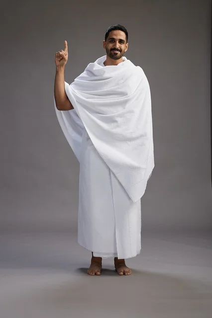 بورتريه لرجل عربي سعودي خليجي يرتدي ملابس الإحرام لأداء مناسك الحج, العباده والتقرب الى الله , الحج والعمره في مكه, الجسم بالطول الكامل , خلفيه رماديه