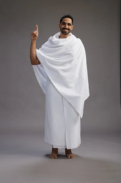 بورتريه لرجل عربي سعودي خليجي يرتدي ملابس الإحرام لأداء مناسك الحج, العباده والتقرب الى الله , الحج والعمره في مكه, الجسم بالطول الكامل , خلفيه رماديه