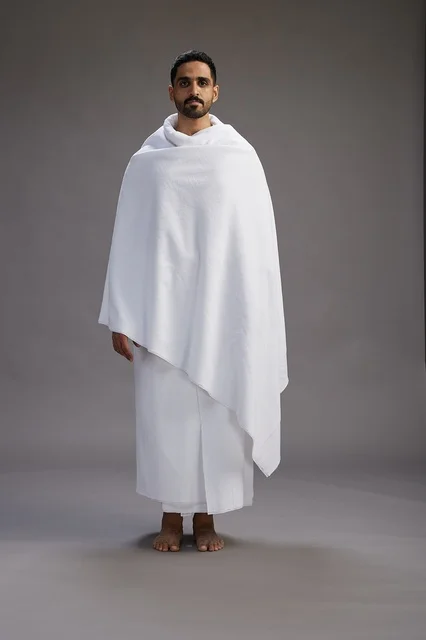 بورتريه لرجل عربي سعودي خليجي يرتدي ملابس الإحرام لأداء مناسك الحج, العباده والتقرب الى الله , الحج والعمره في مكه, الجسم بالطول الكامل , خلفيه رماديه