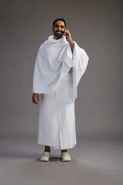 بورتريه لرجل سعودي بملابس الإحرام يجري مكالمة هاتفية عبر الهاتف المحمول, الاستعداد لاداء مناسك الحج والعمره, الجسم بالطول الكامل , خلفيه رماديه بورتريه لرجل سعودي بملابس الإحرام يجري مكالمة هاتفية عبر الهاتف المحمول, الاستعداد لاداء مناسك الحج والعمره, الجسم بالطول الكامل , خلفيه رماديه