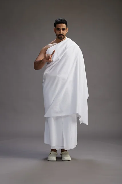 بورتريه لرجل عربي سعودي خليجي يرتدي ملابس الإحرام لأداء مناسك الحج, العباده والتقرب الى الله , الحج والعمره في مكه, الجسم بالطول الكامل , خلفيه رماديه