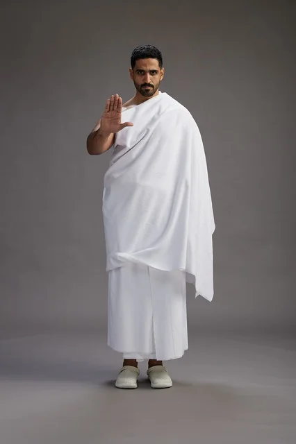 بورتريه لرجل عربي سعودي خليجي يرتدي ملابس الإحرام لأداء مناسك الحج, العباده والتقرب الى الله , الحج والعمره في مكه, الجسم بالطول الكامل , خلفيه رماديه