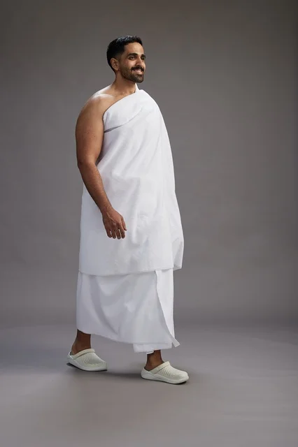 بورتريه لرجل عربي سعودي خليجي يرتدي ملابس الإحرام لأداء مناسك الحج, العباده والتقرب الى الله , الحج والعمره في مكه, الجسم بالطول الكامل , خلفيه رماديه