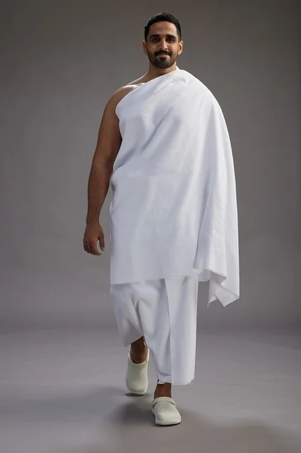 بورتريه لرجل عربي سعودي خليجي يرتدي ملابس الإحرام لأداء مناسك الحج, العباده والتقرب الى الله , الحج والعمره في مكه, الجسم بالطول الكامل , خلفيه رماديه
