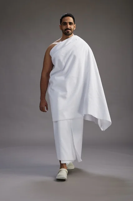 بورتريه لرجل عربي سعودي خليجي يرتدي ملابس الإحرام لأداء مناسك الحج, العباده والتقرب الى الله , الحج والعمره في مكه, الجسم بالطول الكامل , خلفيه رماديه