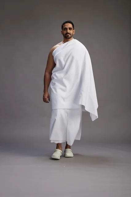 بورتريه لرجل عربي سعودي خليجي يرتدي ملابس الإحرام لأداء مناسك الحج, العباده والتقرب الى الله , الحج والعمره في مكه, الجسم بالطول الكامل , خلفيه رماديه
