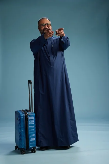 بورتيه لرجل  عربي سعودي  خليجي بثوب أزرق واقف مع حقيبة سفر, الاستعداد للسفر  والسياحه, الجسم بالطول الكامل, خلفيه زرقاء
