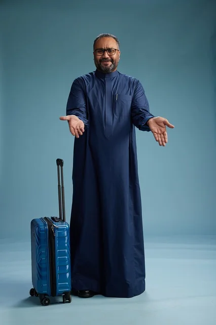 بورتيه لرجل  عربي سعودي  خليجي بثوب أزرق واقف مع حقيبة سفر, الاستعداد للسفر  والسياحه, الجسم بالطول الكامل, خلفيه زرقاء