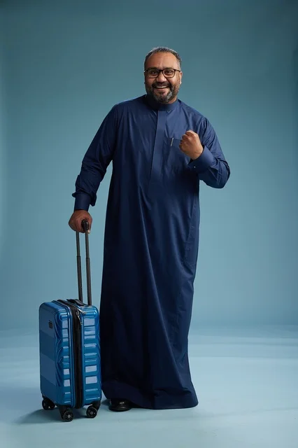 بورتيه لرجل  عربي سعودي  خليجي بثوب أزرق واقف مع حقيبة سفر, الاستعداد للسفر  والسياحه, الجسم بالطول الكامل, خلفيه زرقاء