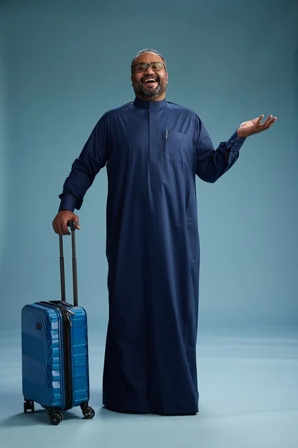 بورتيه لرجل  عربي سعودي  خليجي بثوب أزرق واقف مع حقيبة سفر, الاستعداد للسفر  والسياحه, الجسم بالطول الكامل, خلفيه زرقاء