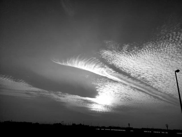 A black and white image of the natural scenery at Al Mamzar Beach, a famous landmark in the United Arab Emirates, a tourist destination to attract and draw in visitors, the coastal waterfront in the city of Dubai, clouds and mist in the sky at sunset.