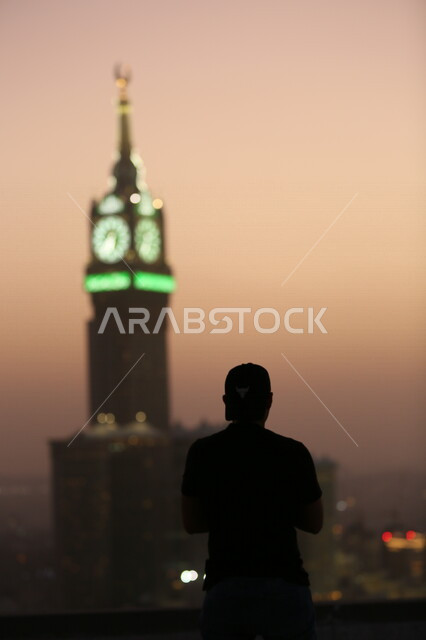 Aesthetic image at sunset of a man standing in front of the clock tower, Mecca, the beauty of Saudi Arabia
