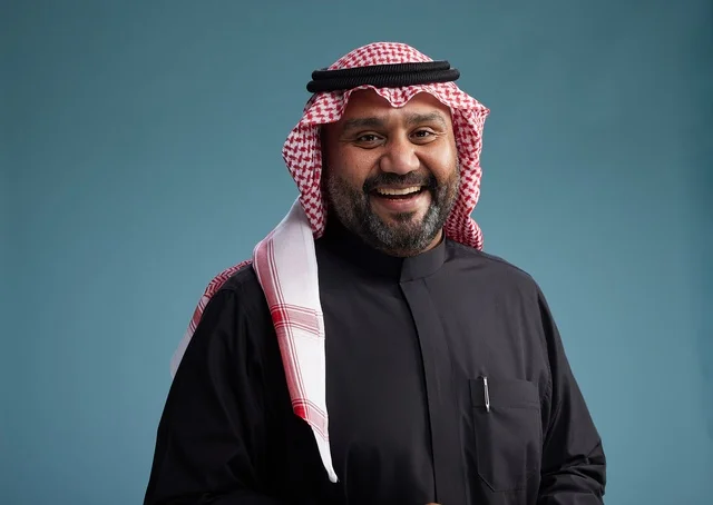 A smiling Saudi man wearing a black thobe with a shemagh and agal, with various hand gestures and movements, against a blue background.