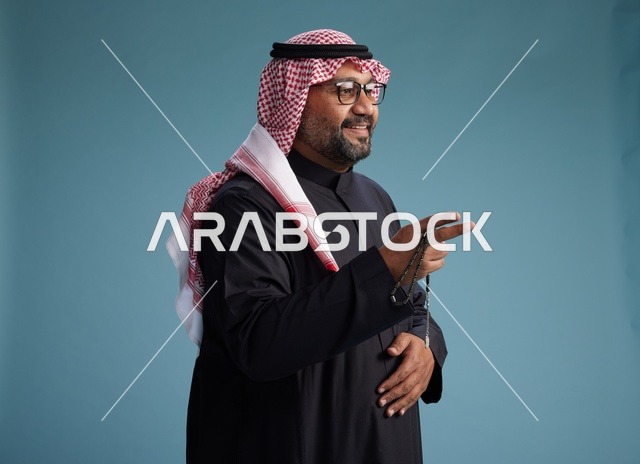 رجل سعودي مبتسم يرتدي ثوب أسود مع شماغ وعقال, ايماءات وحركات يد متنوعه, خلفيه زرقاء